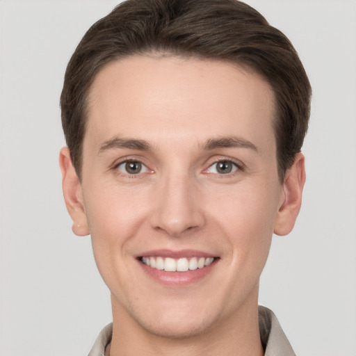 Joyful white young-adult male with short  brown hair and grey eyes