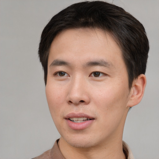 Joyful asian young-adult male with short  brown hair and brown eyes