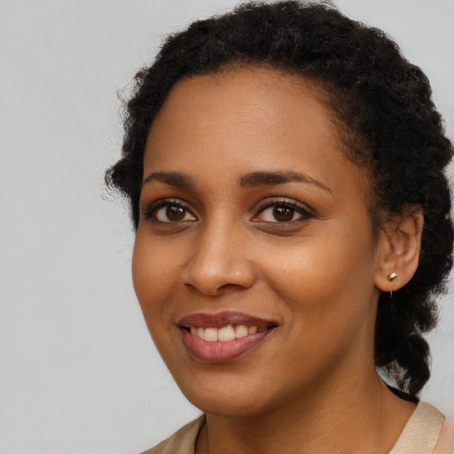 Joyful black young-adult female with long  brown hair and brown eyes