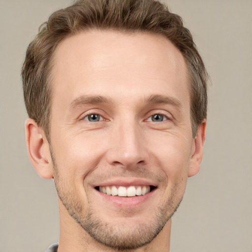 Joyful white young-adult male with short  brown hair and grey eyes