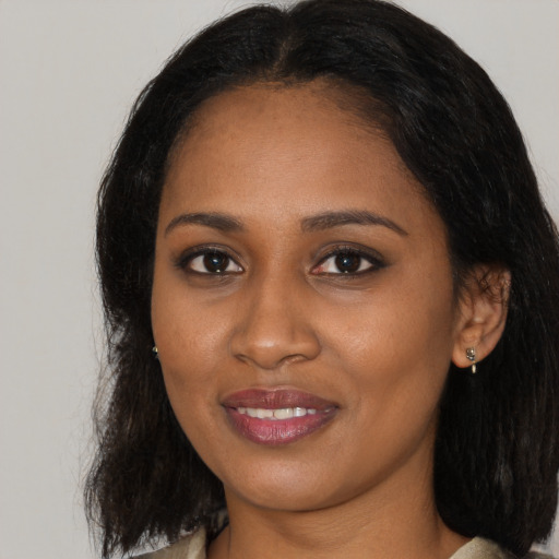 Joyful black young-adult female with long  brown hair and brown eyes