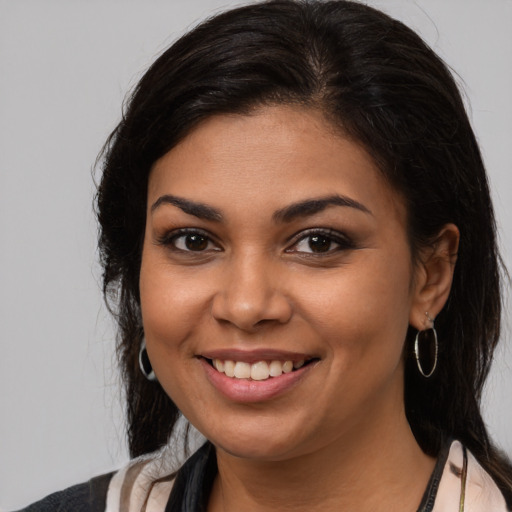 Joyful latino young-adult female with medium  brown hair and brown eyes