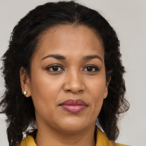 Joyful black adult female with long  brown hair and brown eyes