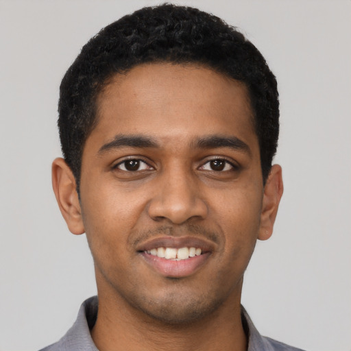 Joyful black young-adult male with short  black hair and brown eyes