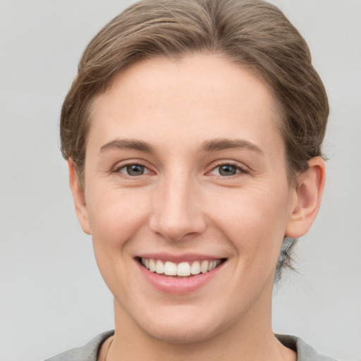 Joyful white young-adult female with short  brown hair and grey eyes