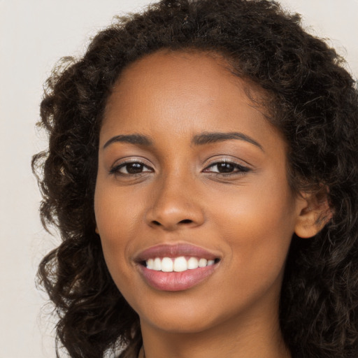 Joyful black young-adult female with long  brown hair and brown eyes