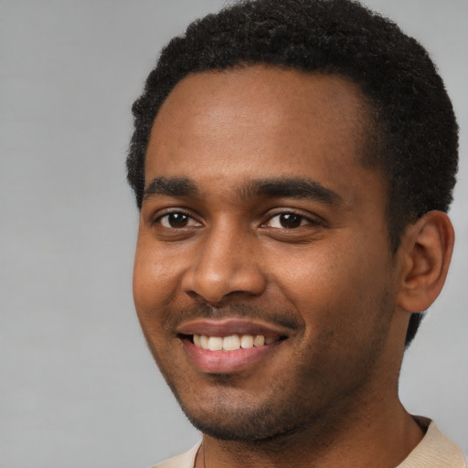 Joyful black young-adult male with short  black hair and brown eyes