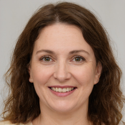 Joyful white adult female with long  brown hair and green eyes