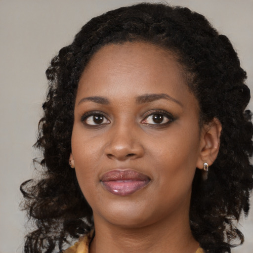 Joyful black young-adult female with long  black hair and brown eyes