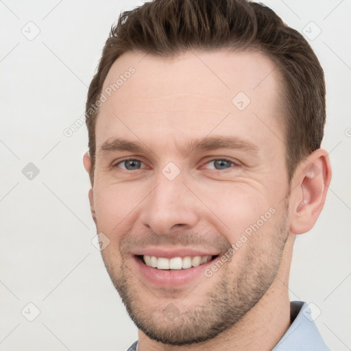 Joyful white young-adult male with short  brown hair and grey eyes