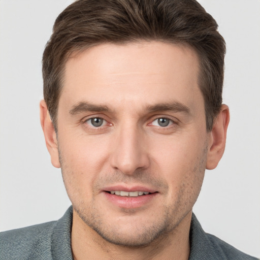 Joyful white young-adult male with short  brown hair and grey eyes