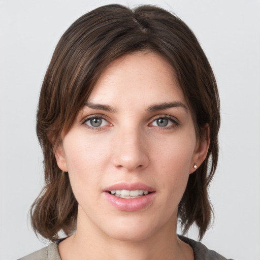 Joyful white young-adult female with medium  brown hair and grey eyes