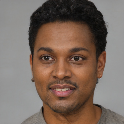 Joyful black young-adult male with short  black hair and brown eyes