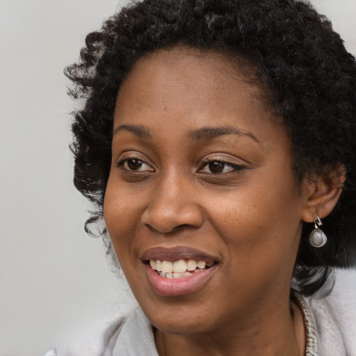 Joyful black young-adult female with long  black hair and brown eyes