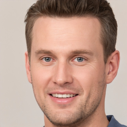 Joyful white young-adult male with short  brown hair and grey eyes