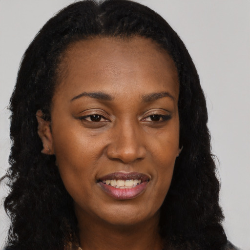Joyful black young-adult female with long  black hair and brown eyes