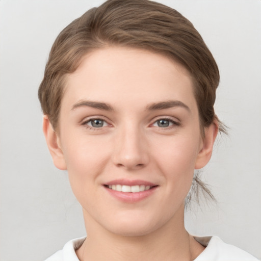 Joyful white young-adult female with short  brown hair and grey eyes