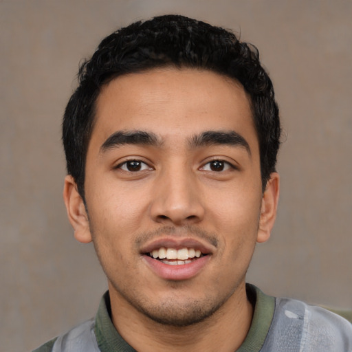 Joyful latino young-adult male with short  black hair and brown eyes
