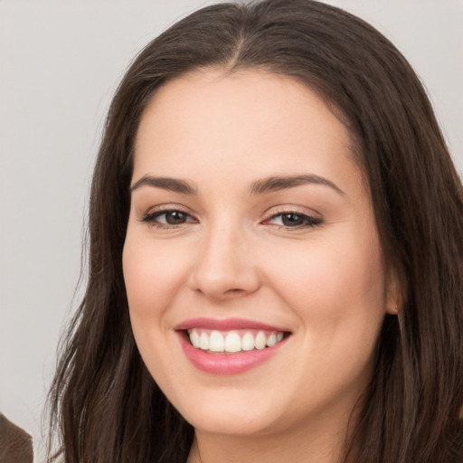 Joyful white young-adult female with long  brown hair and brown eyes