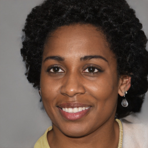 Joyful black young-adult female with short  black hair and brown eyes