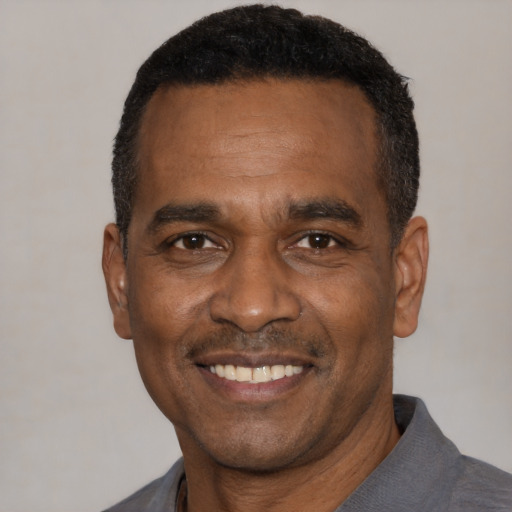 Joyful black adult male with short  black hair and brown eyes