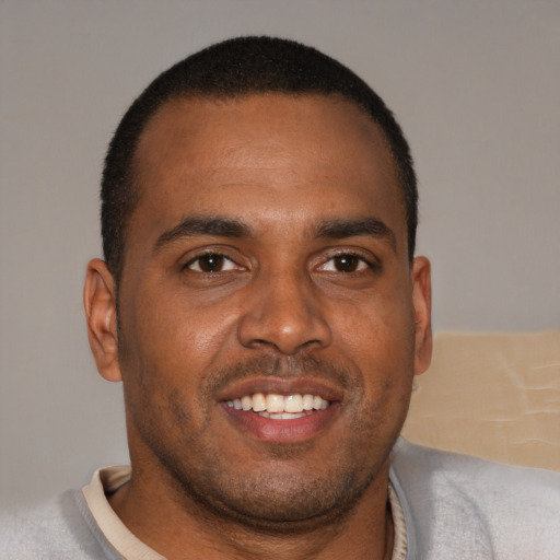 Joyful black young-adult male with short  brown hair and brown eyes