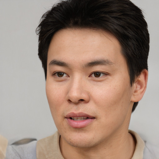 Joyful asian young-adult male with short  brown hair and brown eyes