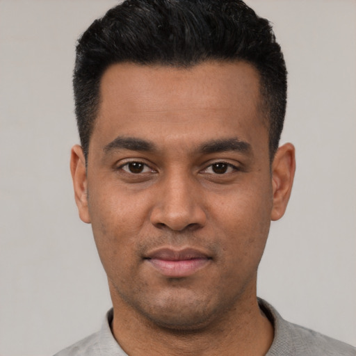 Joyful latino young-adult male with short  black hair and brown eyes