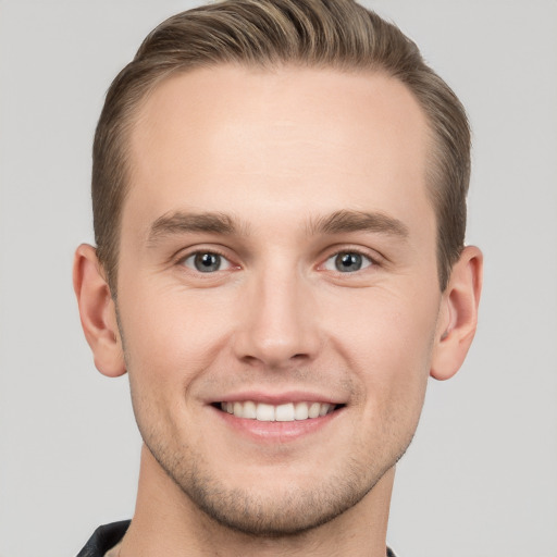 Joyful white young-adult male with short  brown hair and grey eyes