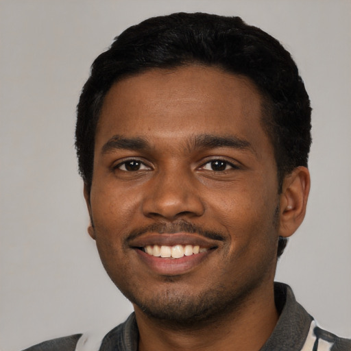 Joyful black young-adult male with short  black hair and brown eyes