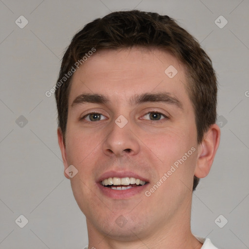 Joyful white young-adult male with short  brown hair and grey eyes