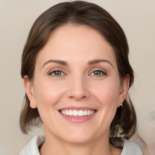 Joyful white young-adult female with medium  brown hair and grey eyes