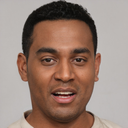 Joyful black young-adult male with short  black hair and brown eyes