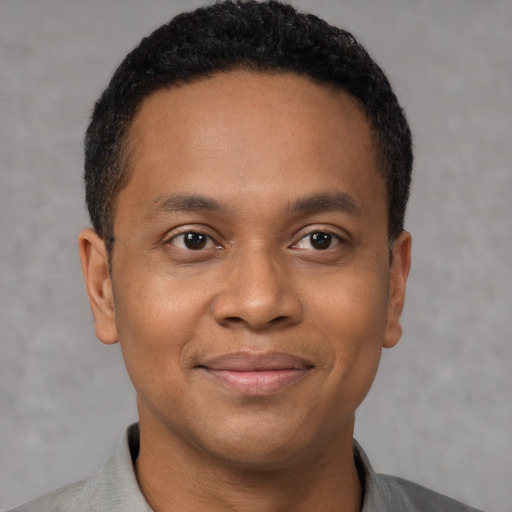 Joyful black young-adult male with short  brown hair and brown eyes