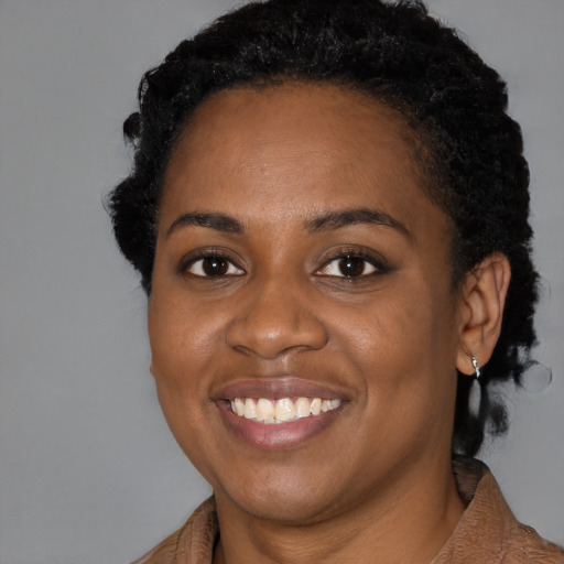 Joyful black young-adult female with short  black hair and brown eyes