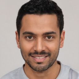 Joyful latino young-adult male with short  black hair and brown eyes