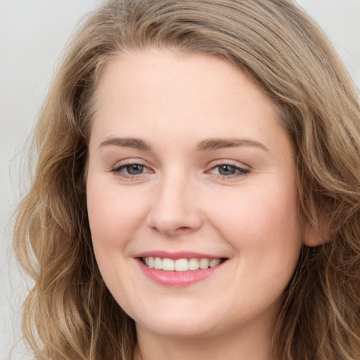 Joyful white young-adult female with long  brown hair and blue eyes