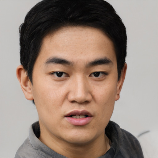 Joyful asian young-adult male with short  black hair and brown eyes