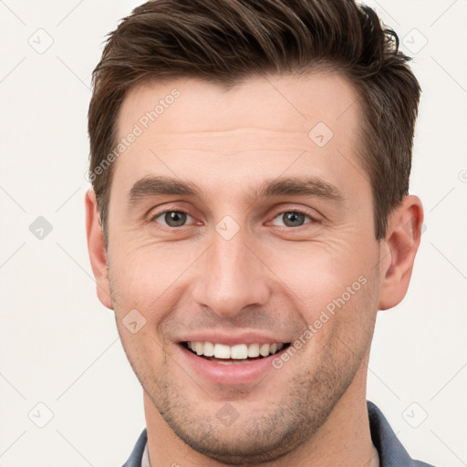 Joyful white young-adult male with short  brown hair and grey eyes