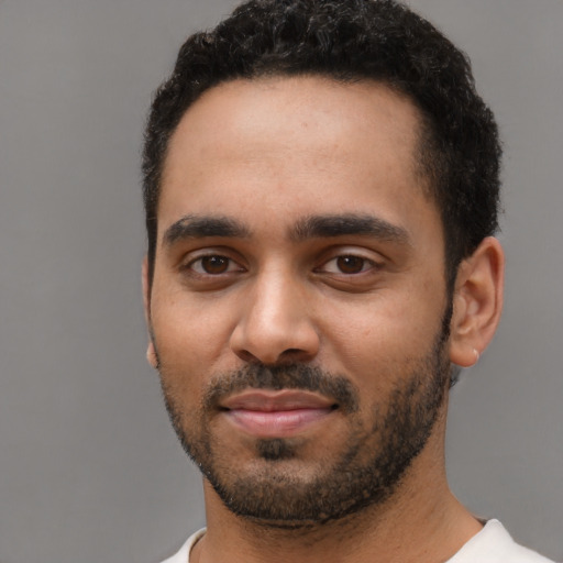 Joyful black young-adult male with short  black hair and brown eyes