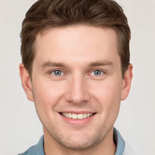 Joyful white young-adult male with short  brown hair and grey eyes