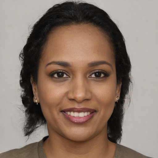 Joyful black young-adult female with long  brown hair and brown eyes