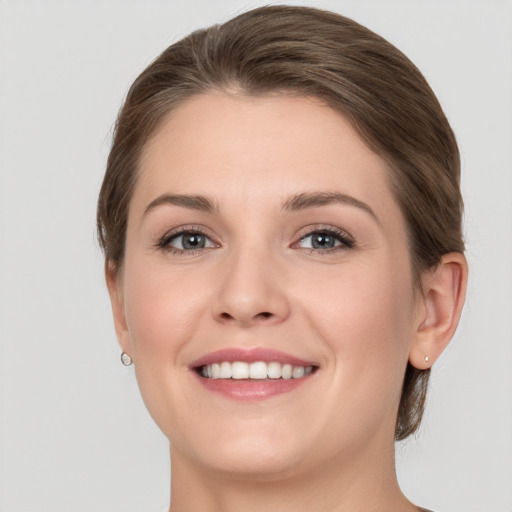 Joyful white young-adult female with medium  brown hair and grey eyes