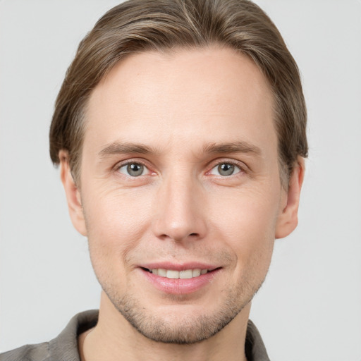 Joyful white young-adult male with short  brown hair and grey eyes