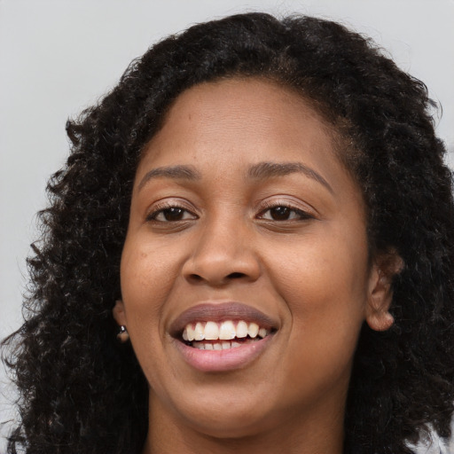 Joyful black young-adult female with long  brown hair and brown eyes