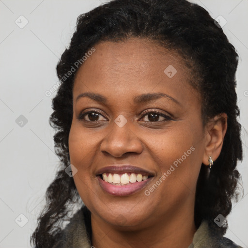 Joyful black young-adult female with long  brown hair and brown eyes