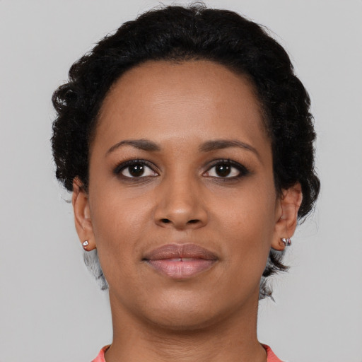 Joyful black young-adult female with short  black hair and brown eyes
