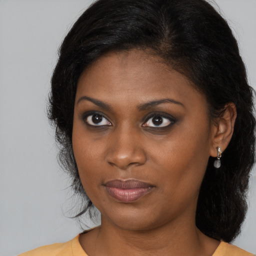 Joyful black young-adult female with long  brown hair and brown eyes