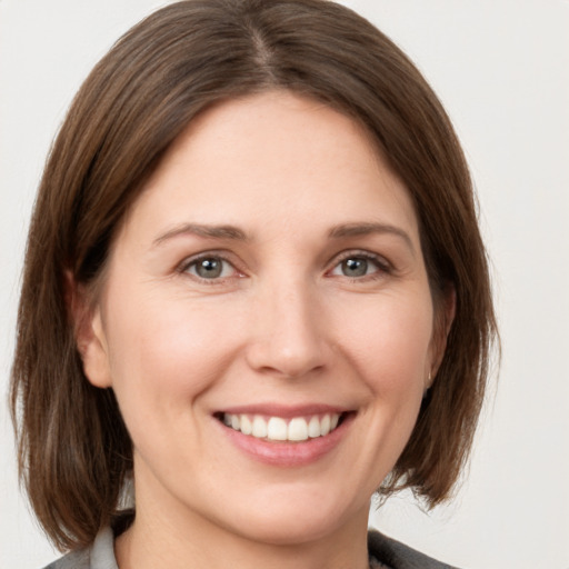 Joyful white young-adult female with medium  brown hair and grey eyes