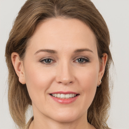 Joyful white young-adult female with long  brown hair and grey eyes